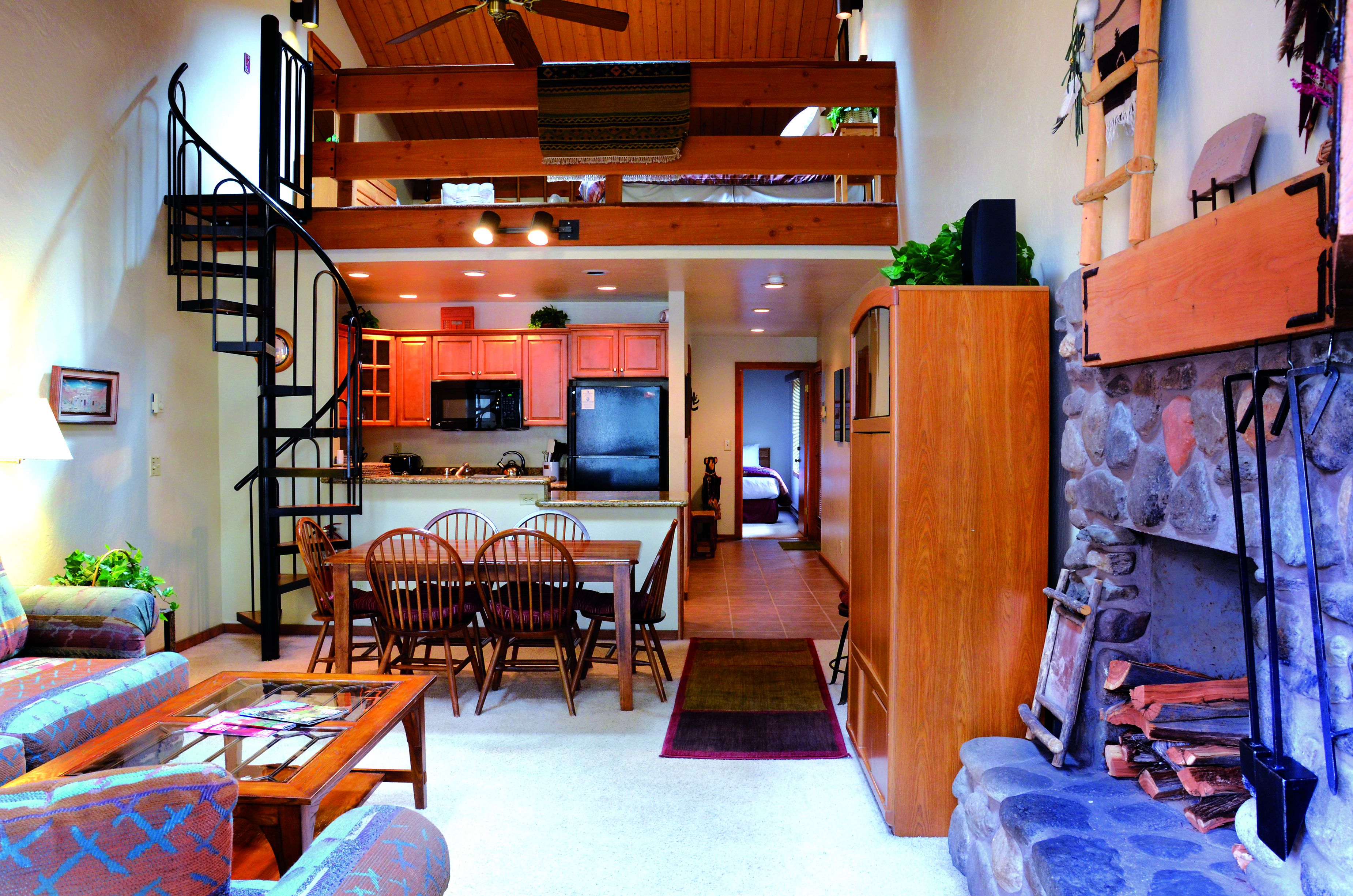 Un amplio salón con una mesa de comedor, sillas, un sofá y una escalera que conduce a un nivel superior.