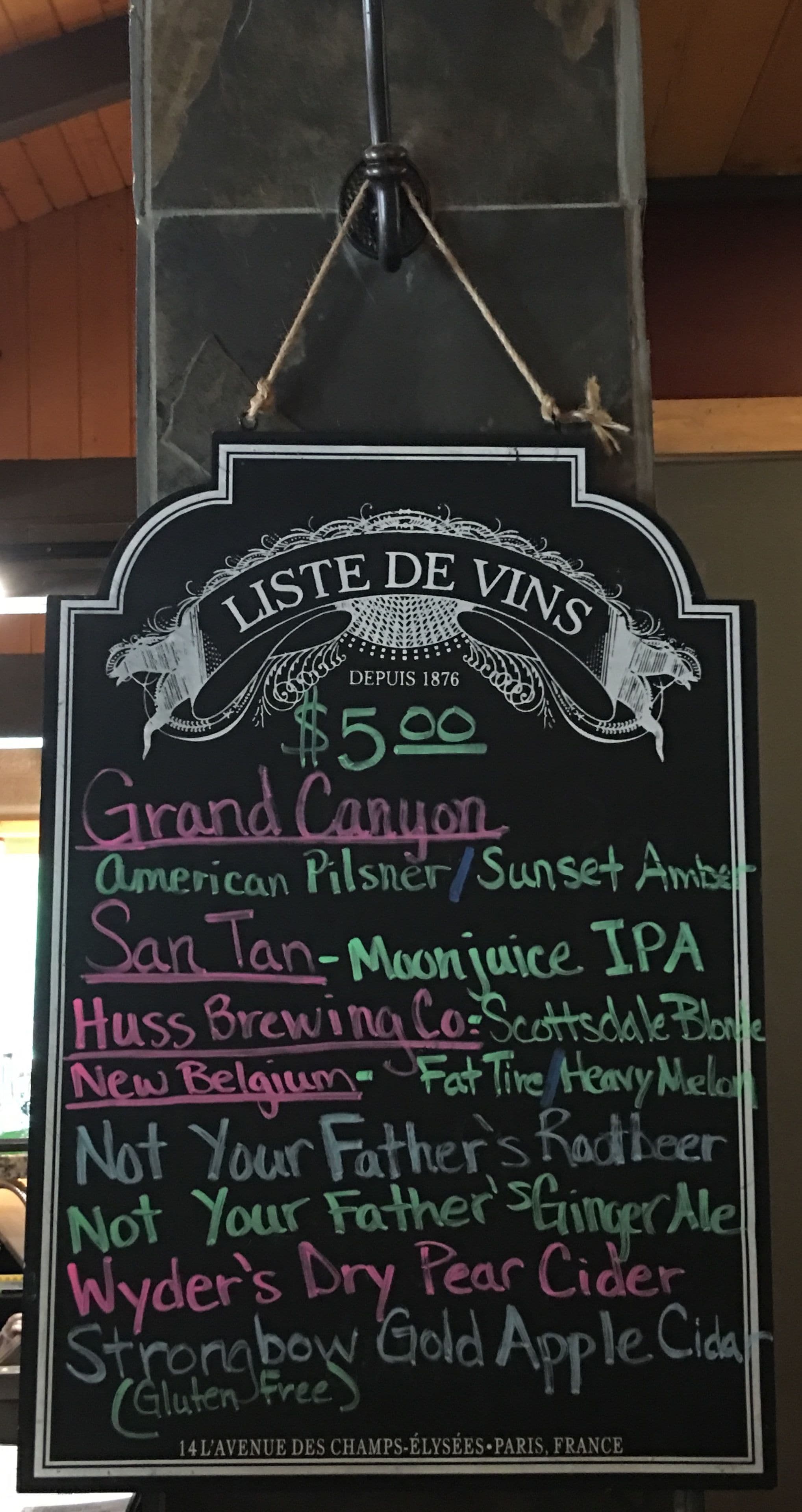 A chalkboard menu listing various wines and their prices, with a price of $5.00 for the Grand Canyon wine.