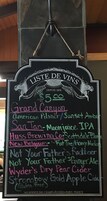 A chalkboard menu listing various wines and their prices, with a price of $5.00 for the Grand Canyon wine.