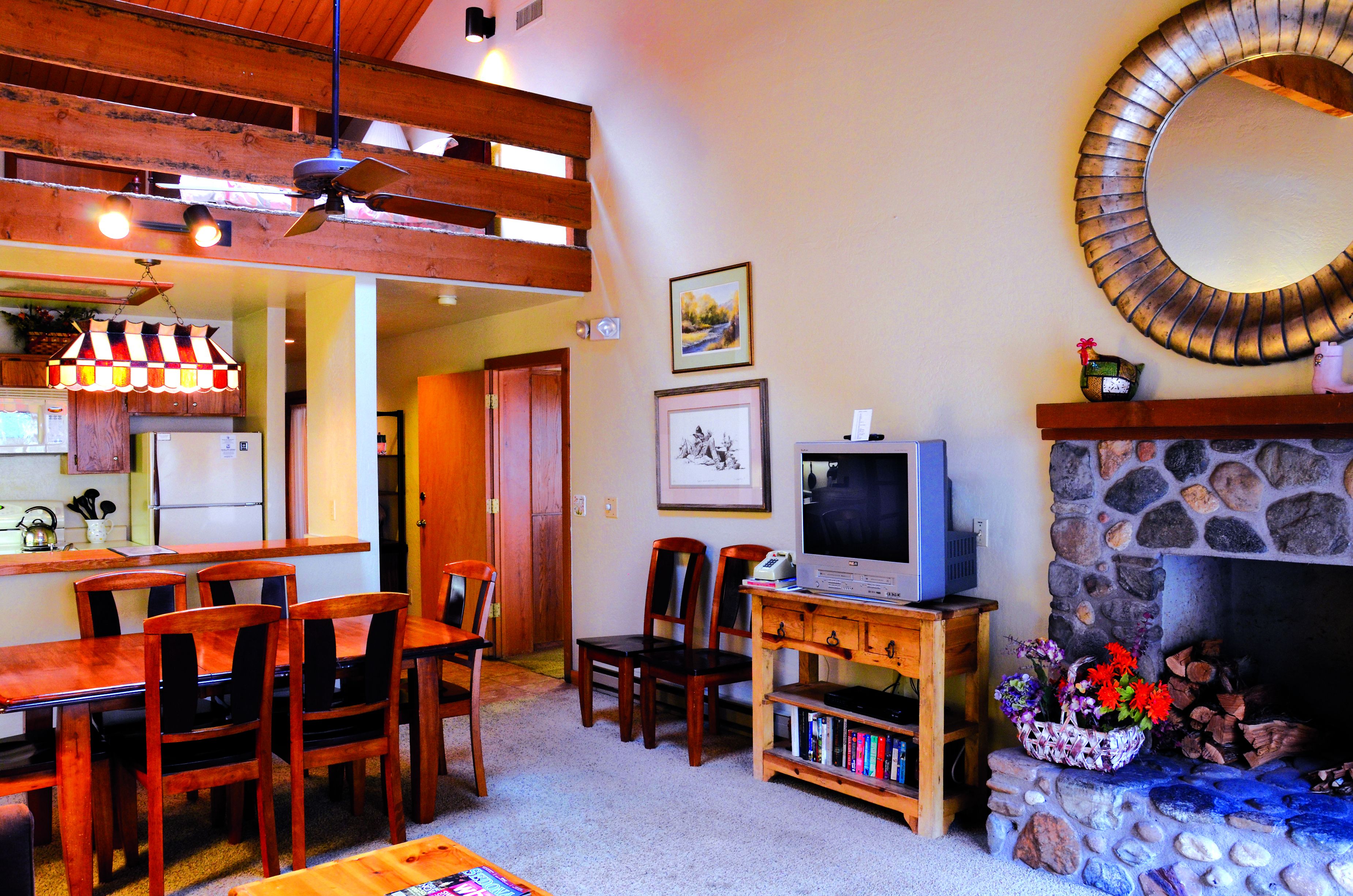 A cozy living room with a dining area, a fireplace, and a television.