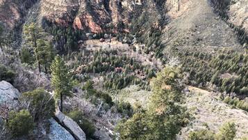 A mountainous area with scattered houses surrounded by dense forests and rocky terrain.