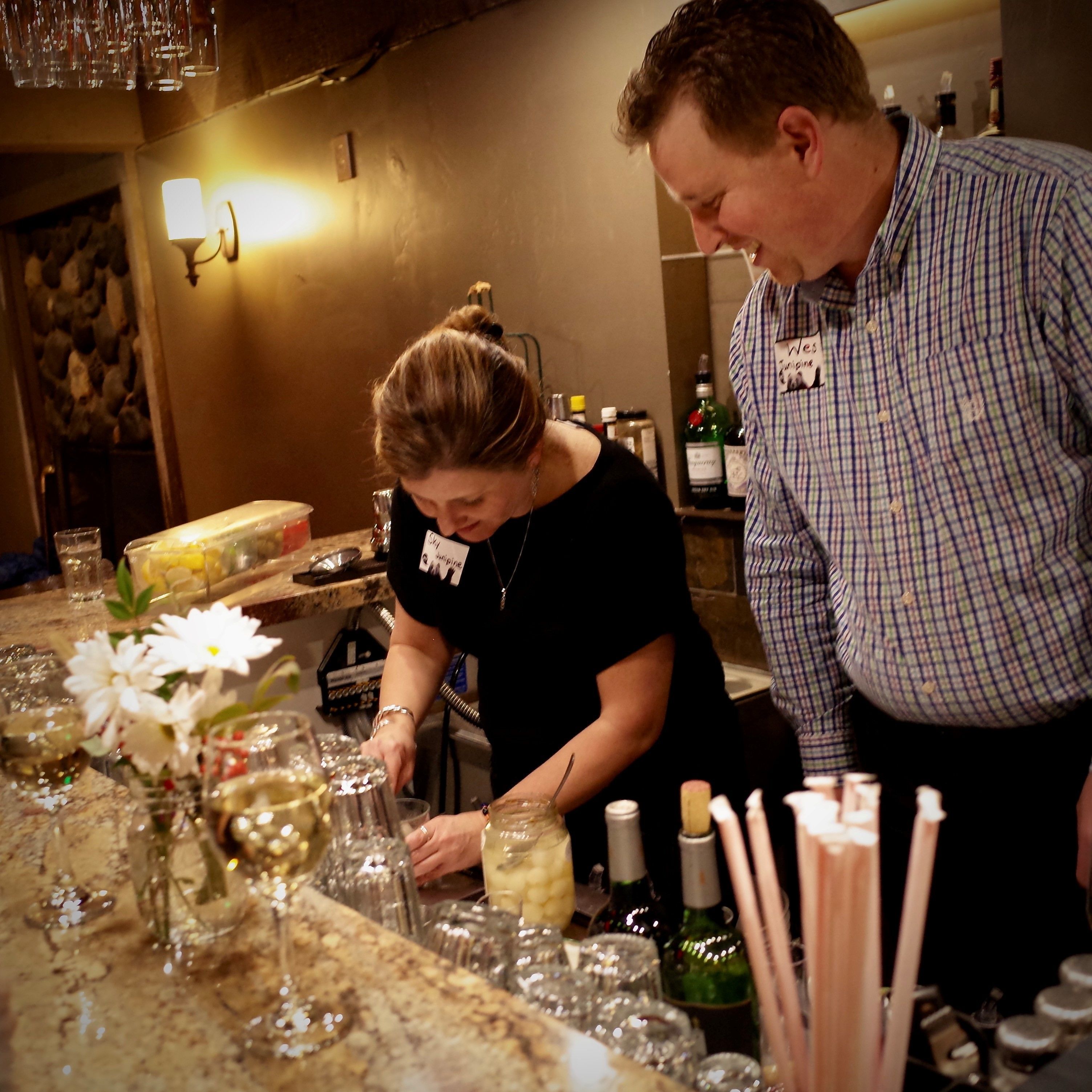 Un espace bar avec un comptoir, des verres, des bouteilles et un arrangement floral.