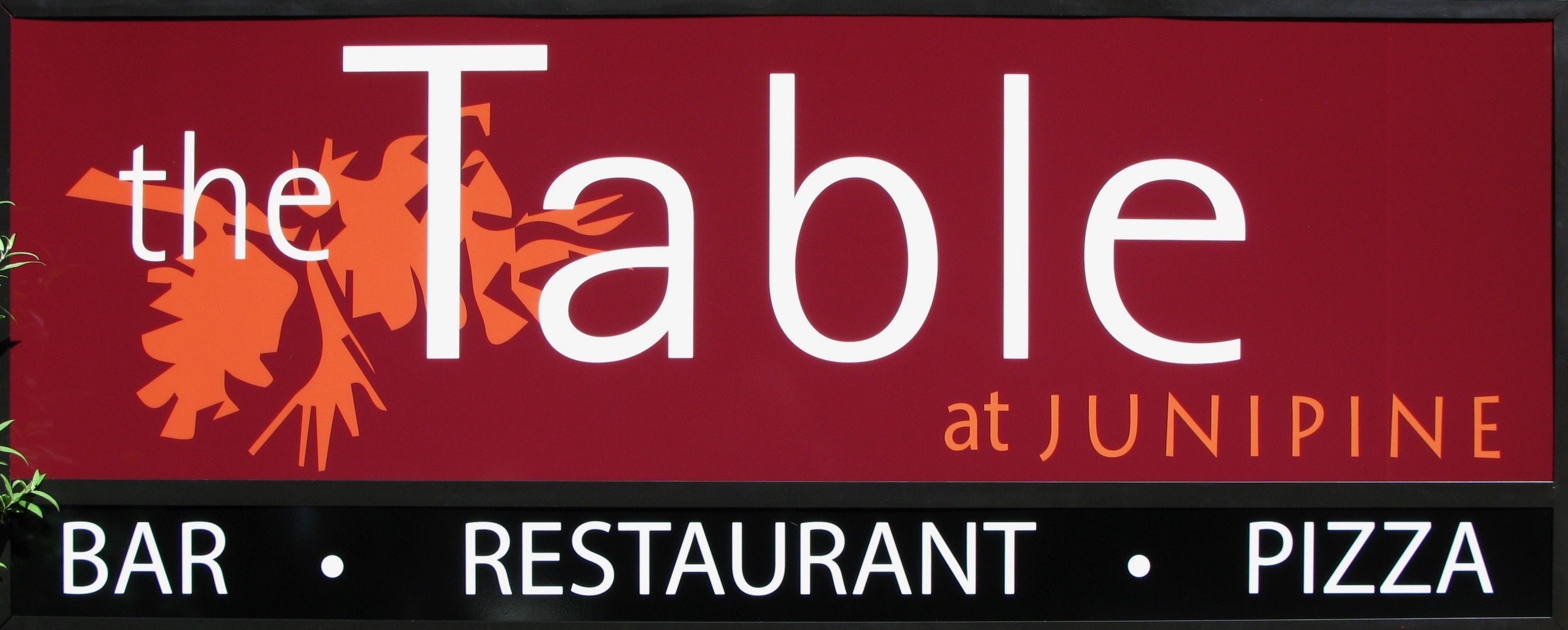 A sign for 'The Table at Junipine' which is a bar, restaurant, and pizza place.