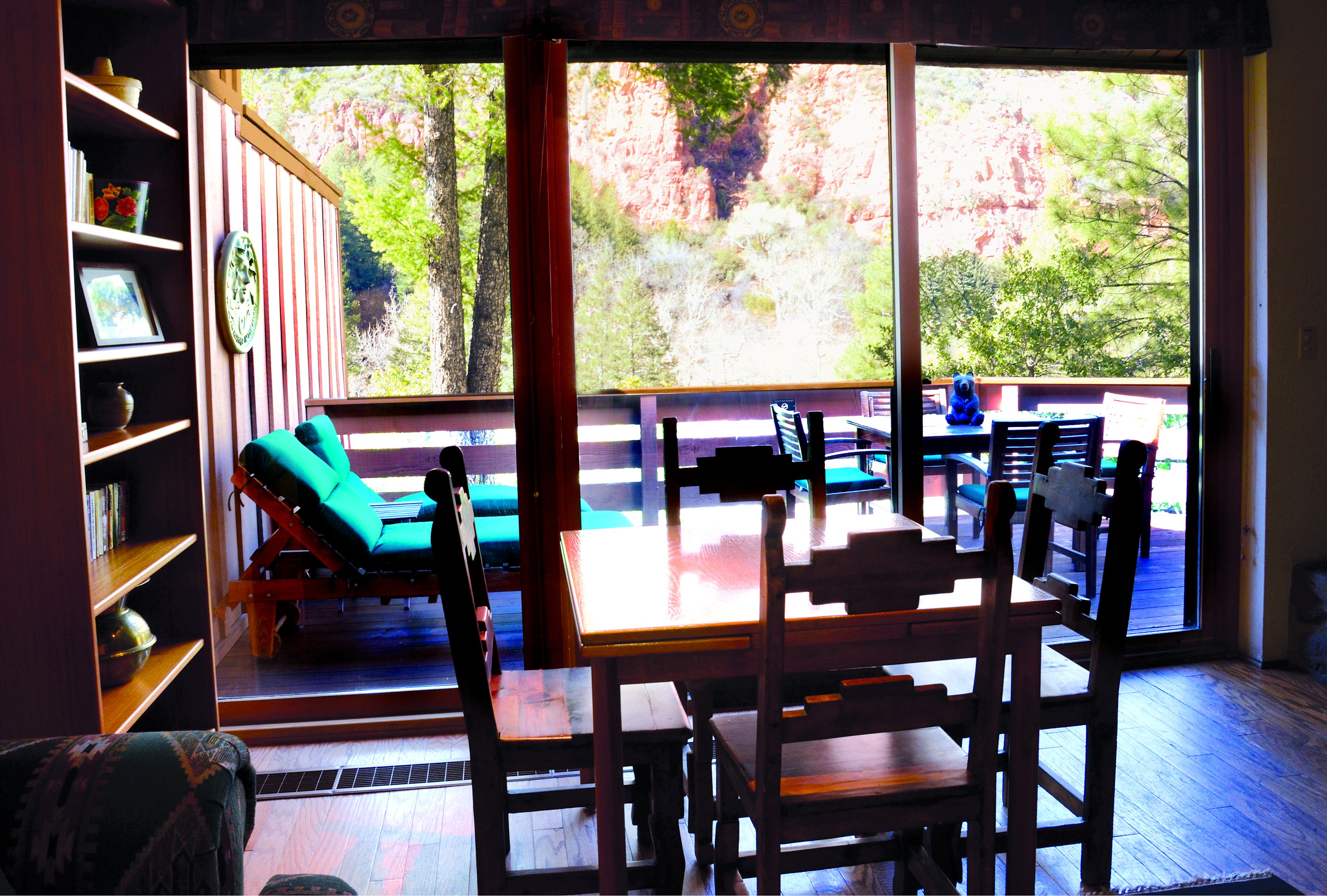 Una habitación con un ventanal grande, una mesa de madera y un sofá verde.