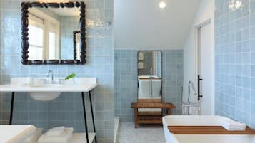 A bathroom with a white sink, a wooden vanity, a large mirror, and a bathtub.
