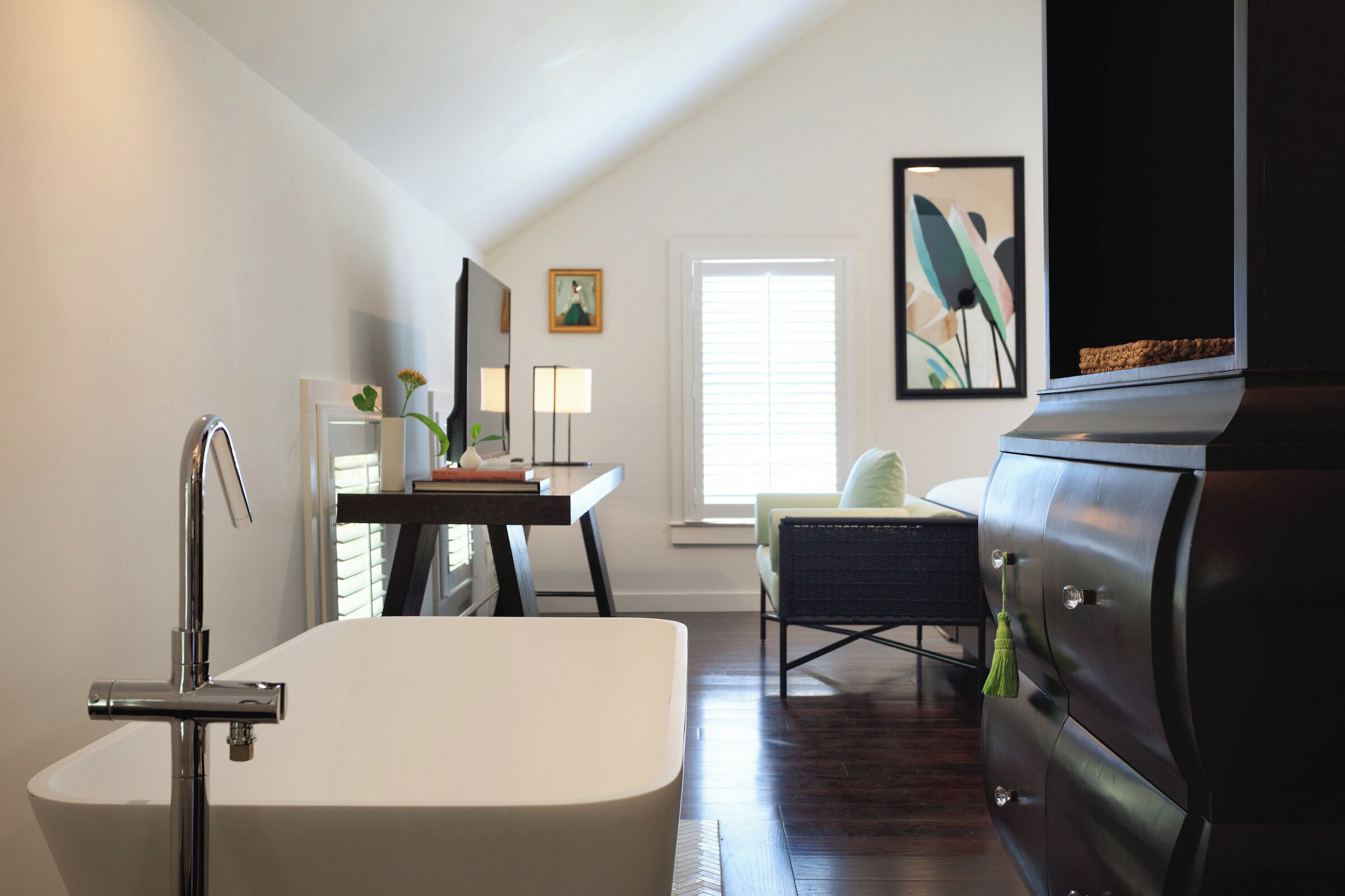 A modern bathroom with a freestanding bathtub, a vanity with a mirror, and a chair.