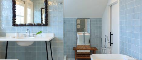 Un baño con lavamanos blanco, tocador de madera y bañera.