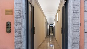 A corridor with doors on both sides, a plaque on the left wall, and a sign at the end. - Townhouse Condotti 29 (Rome)