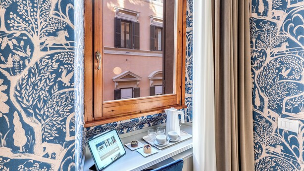A room with a window, a laptop, a cup, and a plate with a pastry. - Townhouse Condotti 29 (Rome)