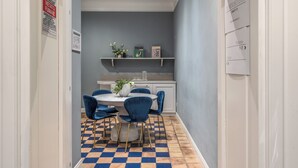 A modern kitchen with a blue and white color scheme, a dining area with blue chairs and a round table, and a checkered floor pattern. - Townhouse Condotti 29 (Rome)