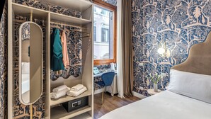 A bedroom with a large bed, a wardrobe with a mirror, a desk with a chair, and a window with curtains. - Townhouse Condotti 29 (Rome)
