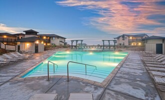 Una piscina con sillones de descanso, un área de estar cubierta y casas al fondo.