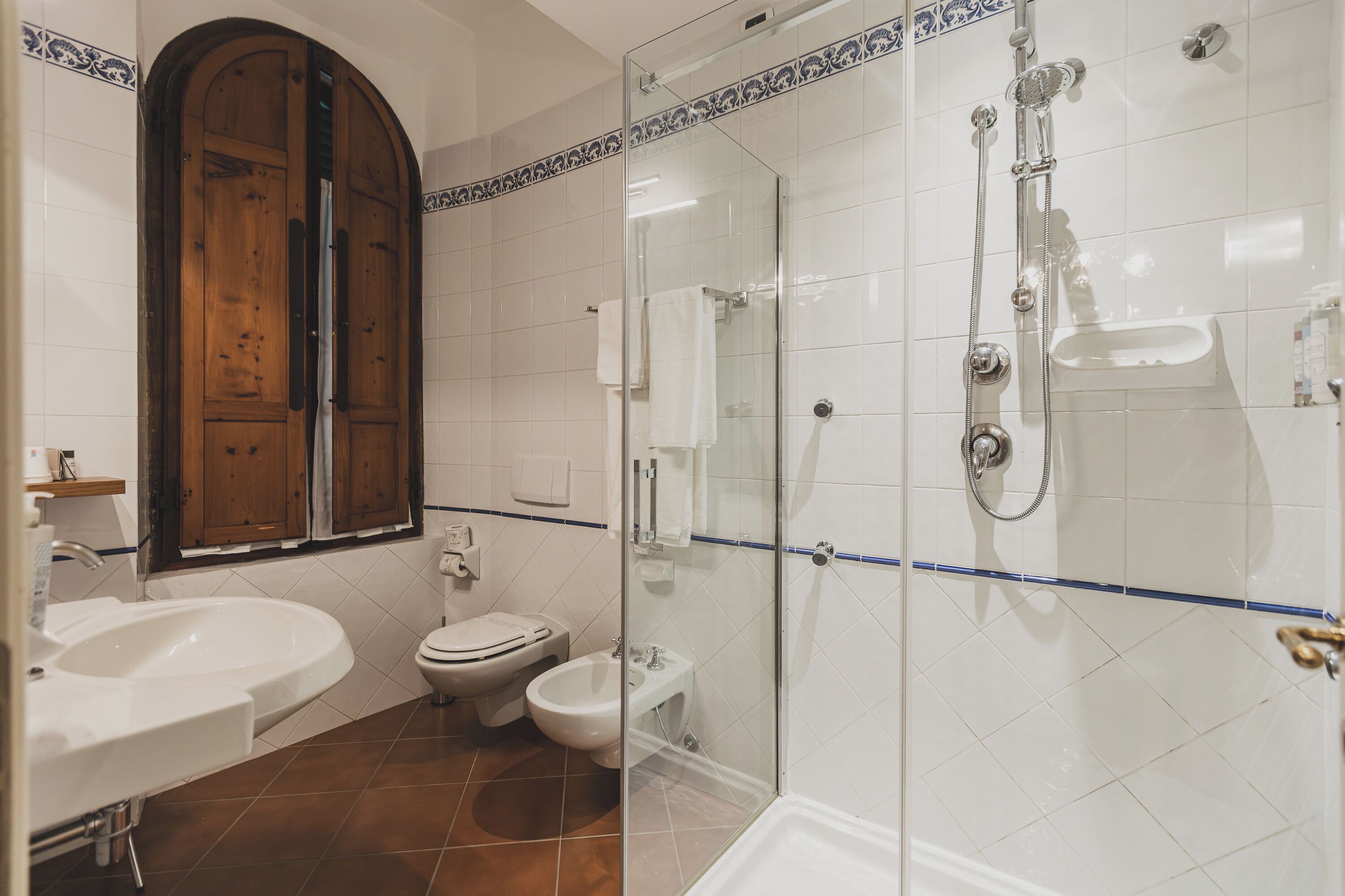 Une salle de bain avec une douche à parois de verre, un lavabo, des toilettes et un bidet.