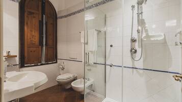 Une salle de bain avec une douche à parois de verre, un lavabo, des toilettes et un bidet.