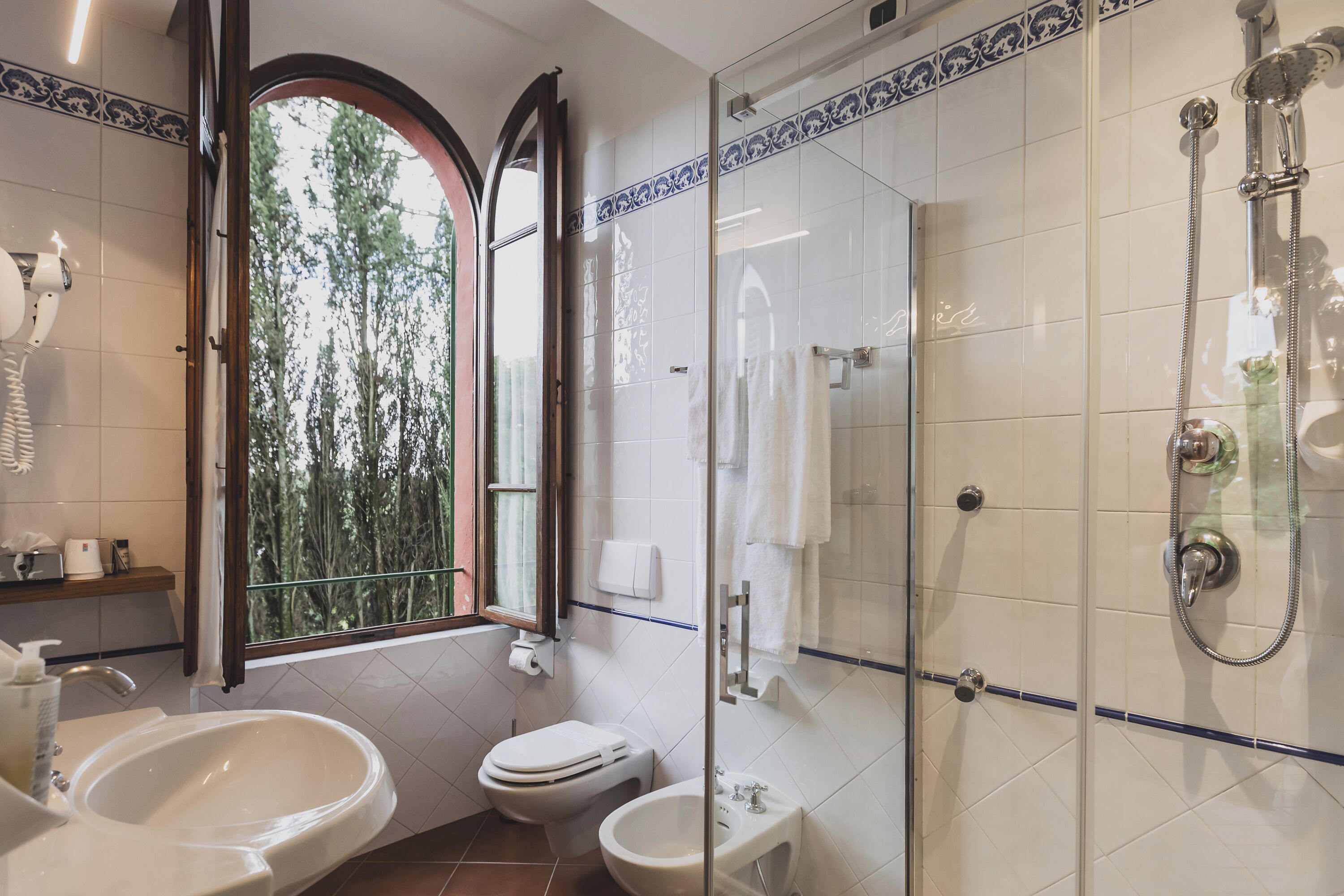 A bathroom with a glass-enclosed shower, a toilet, a bidet, and a sink.