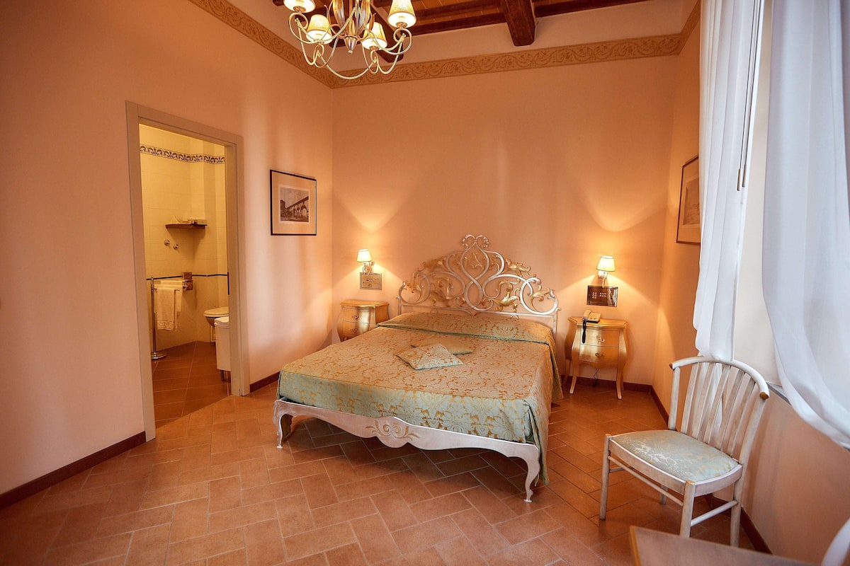 Relax in a classic bedroom with a large bed, ornate headboard, and a nightstand with a lamp.