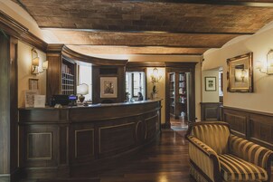 Un área de recepción con un mostrador de madera, un sillón a rayas y techo de ladrillo.