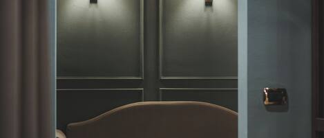 A room with a sofa, two wall-mounted lamps, and a door.