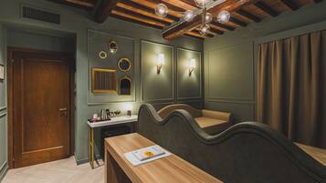 Una stanza con soffitto in legno, una scrivania con un libro, una panca e luci a parete.