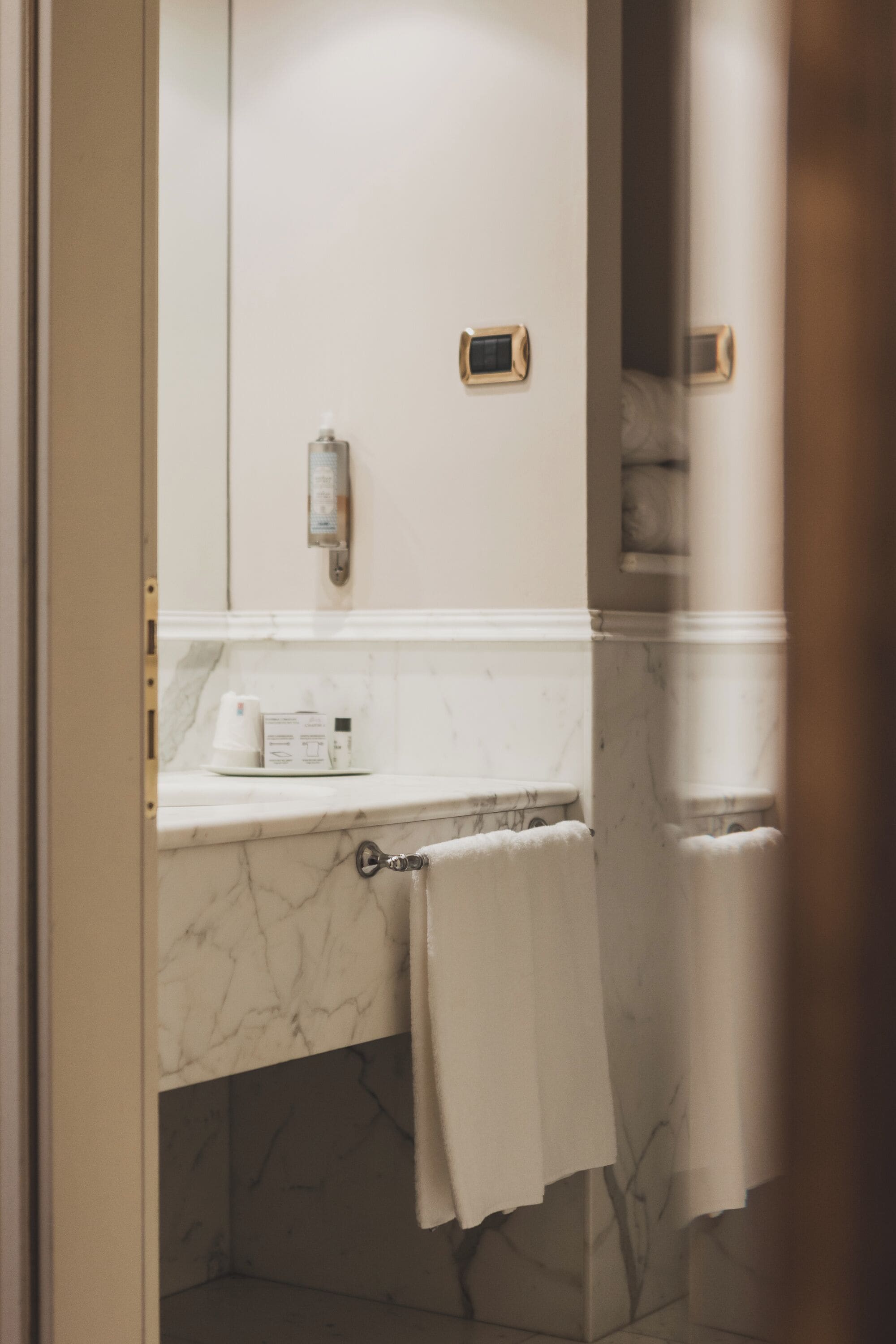 A bathroom with a marble countertop, a towel rack, and a mirror.