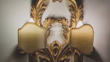 A wall-mounted light fixture with ornate, gold-colored metalwork and two lampshades.