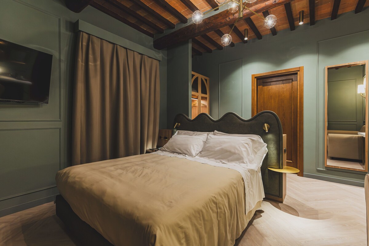 Un dormitorio con cama, televisión, techo de madera y una puerta.