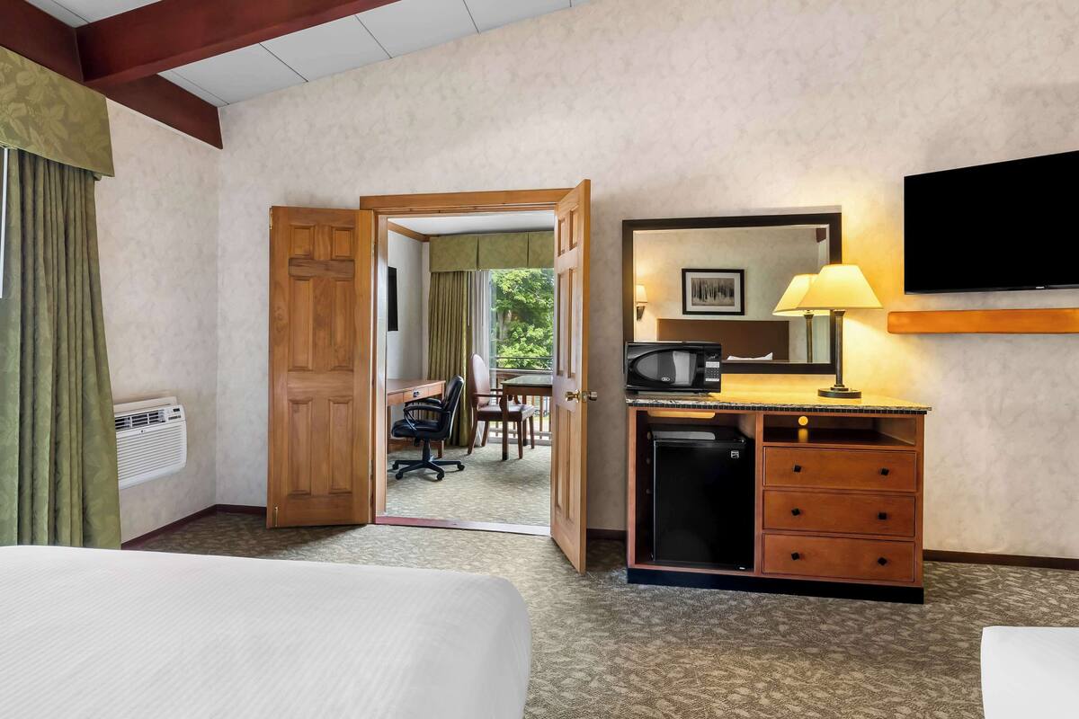 A hotel room with a bed, a desk with a lamp, a television, and a wardrobe.