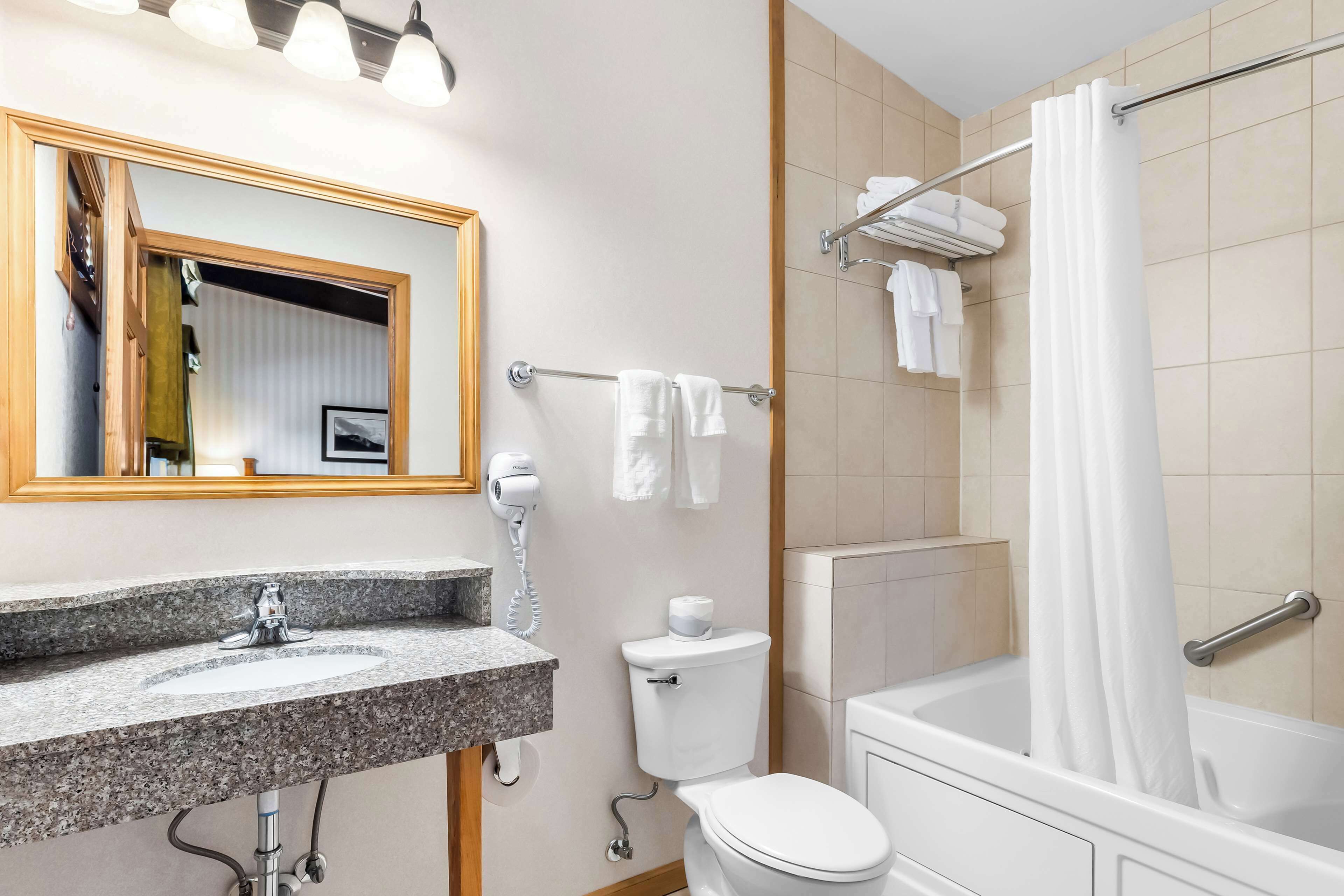 Une salle de bain moderne avec un lavabo en granit, des toilettes, une baignoire et un rideau de douche.