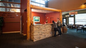 Un espace d’accueil doté d’un comptoir en pierre, de poutres en bois et d’une enseigne indiquant « Vimy’s Lounge & Grill ».