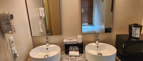A bathroom with two sinks, a hairdryer, and a mirror.