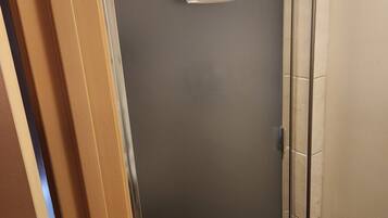 Een douchecabine met glazen wanden, met een witte handdoek aan een metalen stang.
