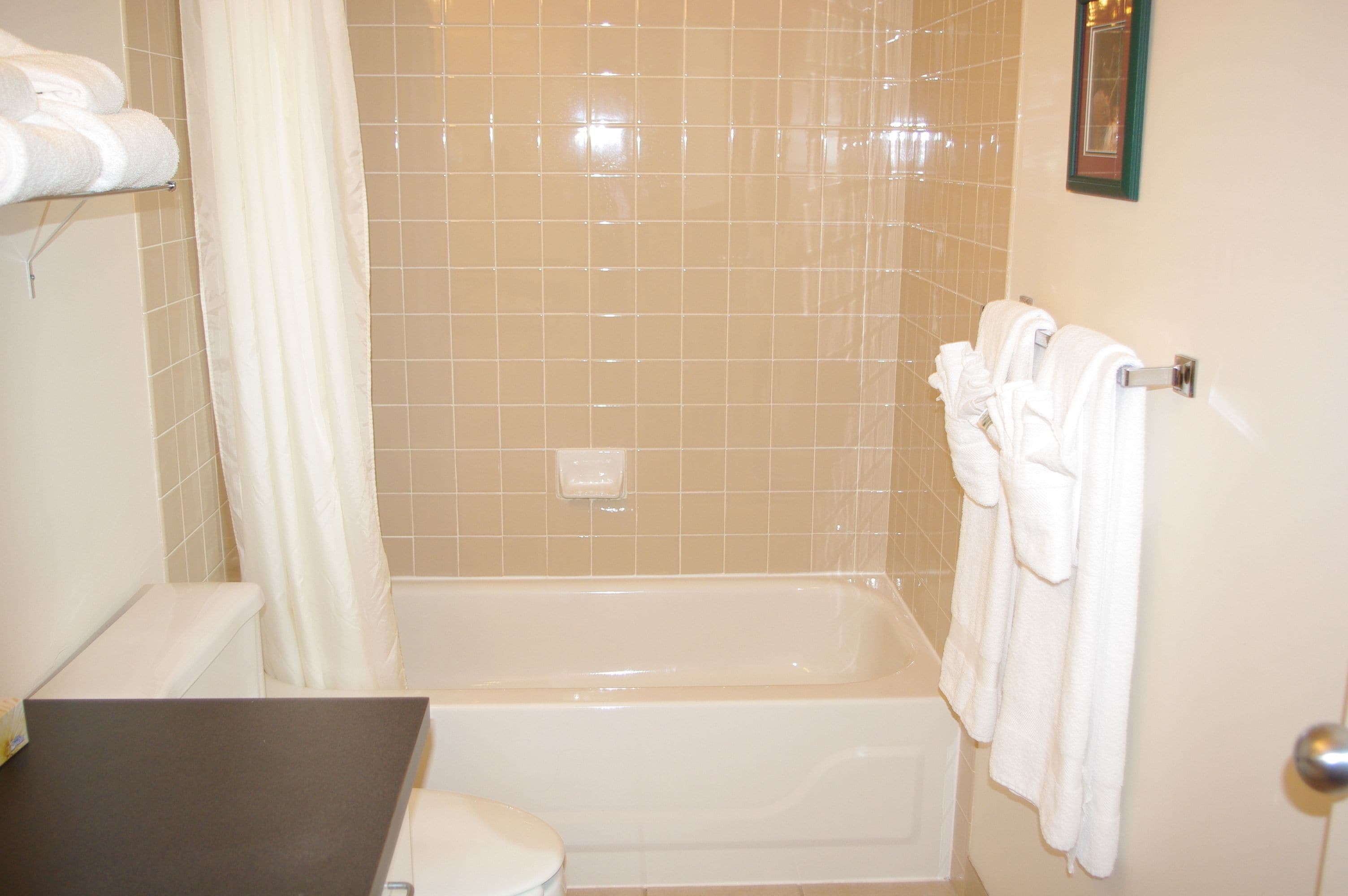 A bathroom with a bathtub, toilet, and a towel rack with towels.