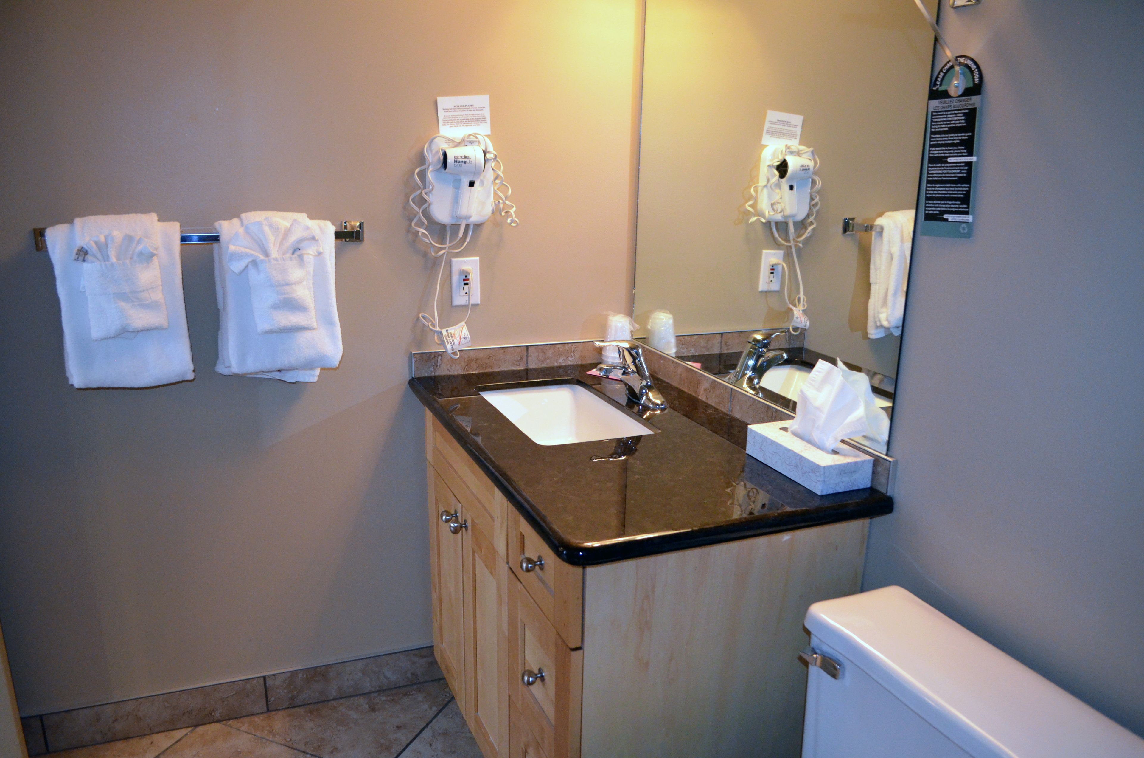 A bathroom with a sink, mirror, towel rack, and toilet.