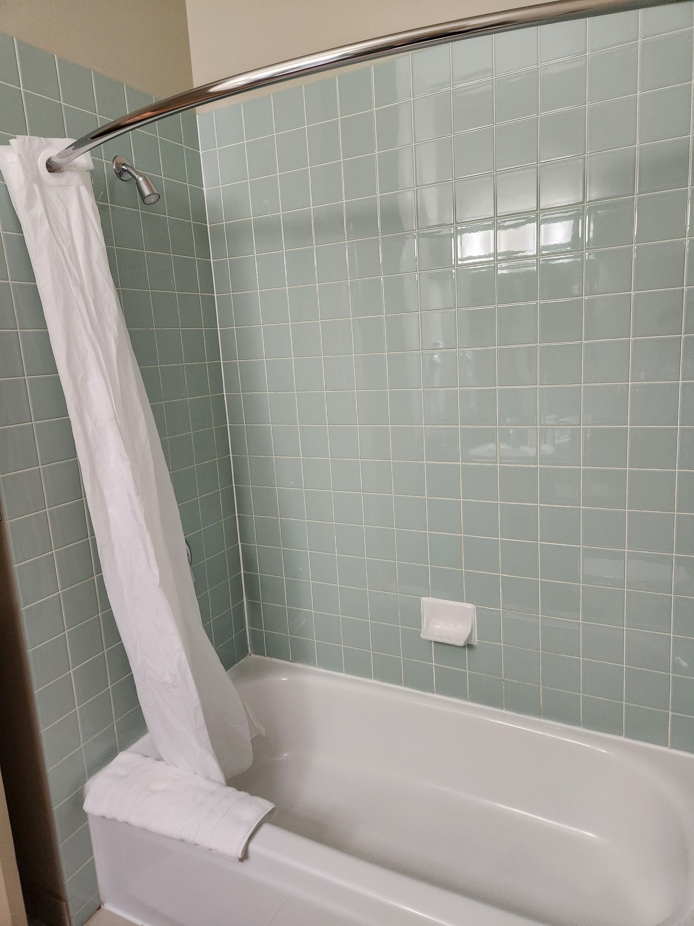 Een badkamer met een badkuip, douchegordijn en betegelde muren.