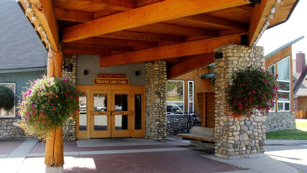 L’entrée du Waterton Lakes Lodge se distingue par sa façade en pierre, ses poutres en bois et ses jardinières suspendues.