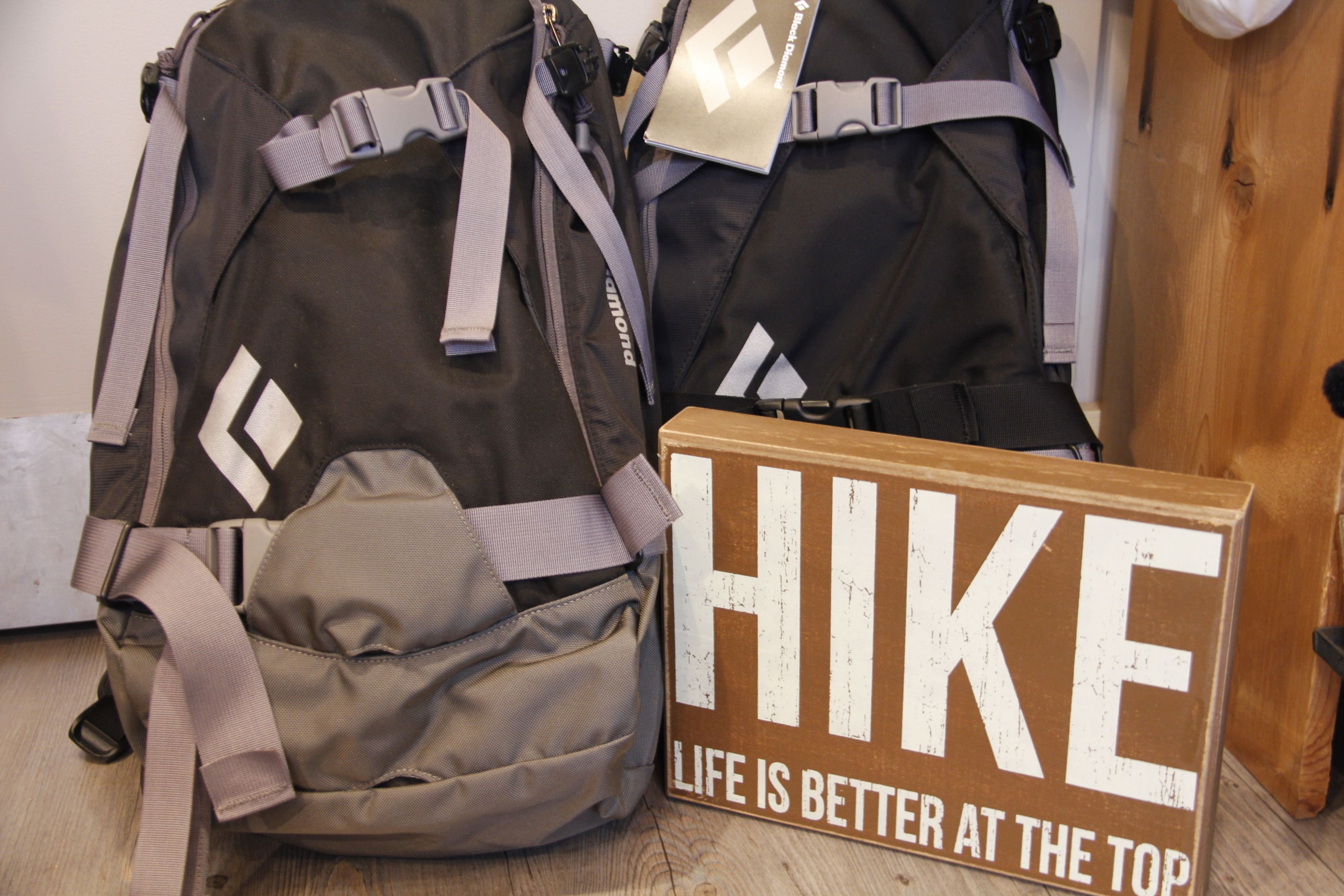 Two backpacks and a sign with the text "HIKE LIFE IS BETTER AT THE TOP".