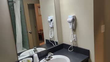 Un bany amb un lavabo blanc, un mirall i dos assecagats de pèl fixats a la paret.
