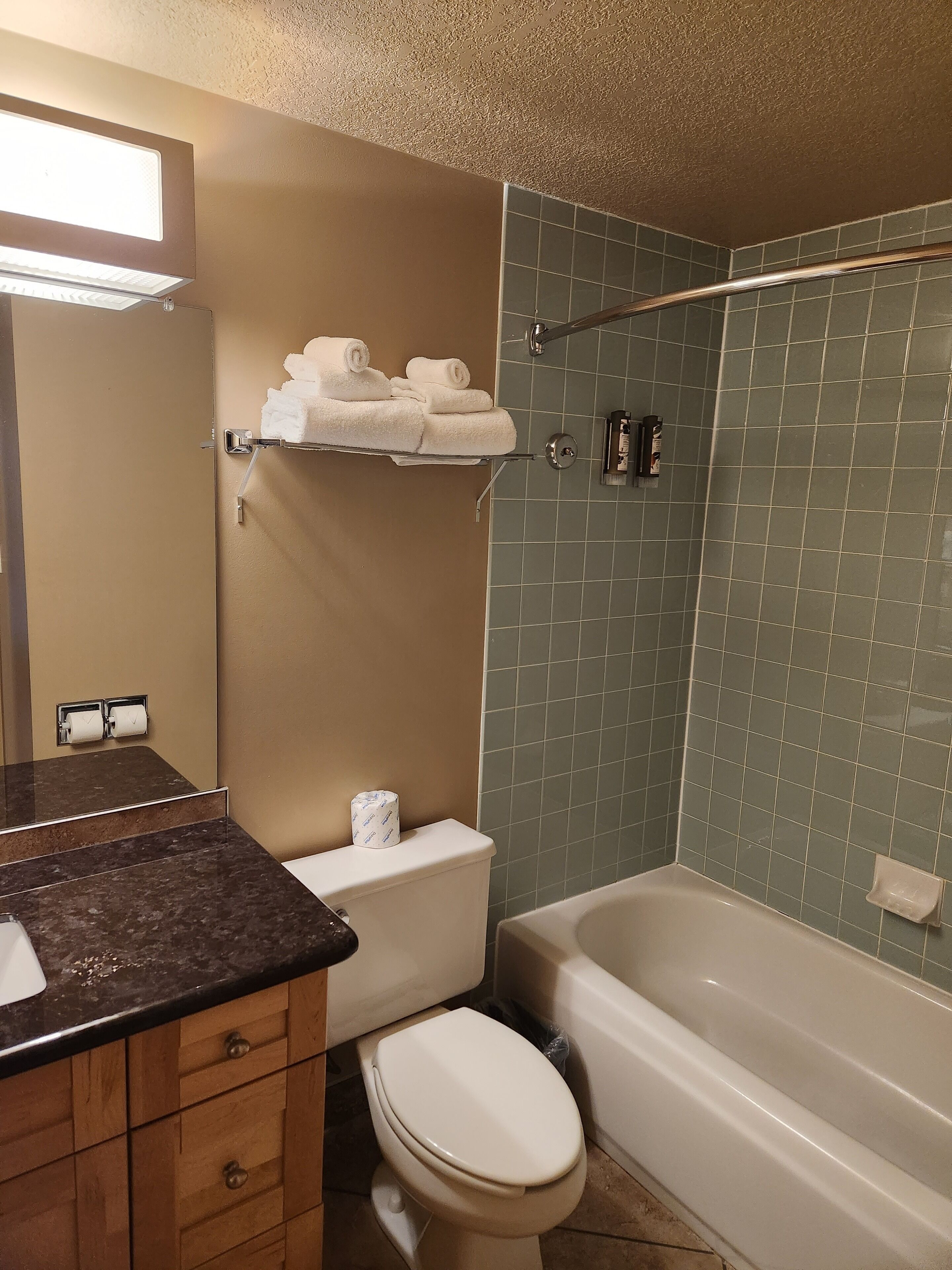 A bathroom with a toilet, sink, and bathtub. There are towels on a rack and a shower curtain rod.