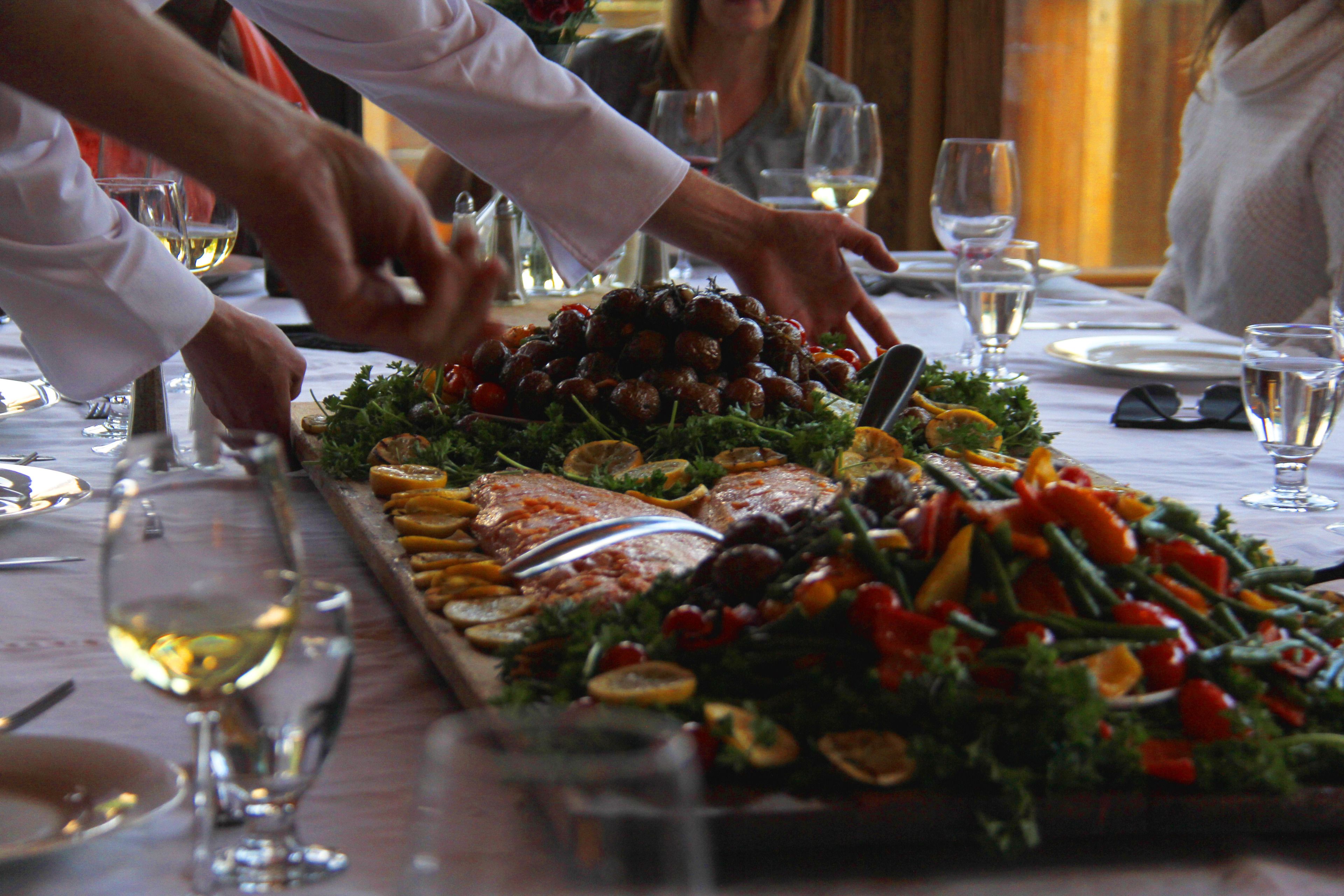 A buffet table with a variety of food items and glasses of white wine.
