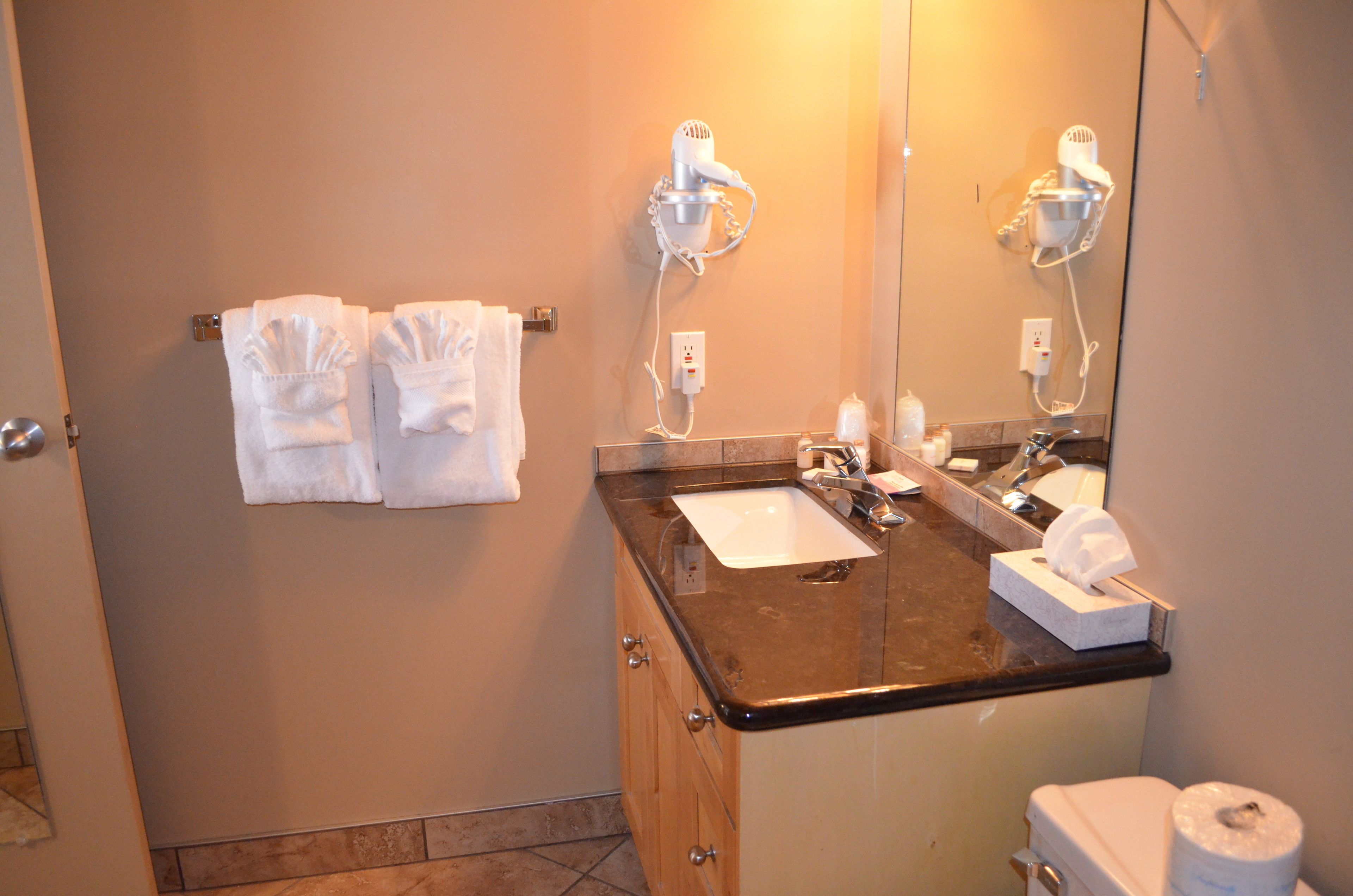 A bathroom with a sink, two towel racks, a mirror, and a toilet.