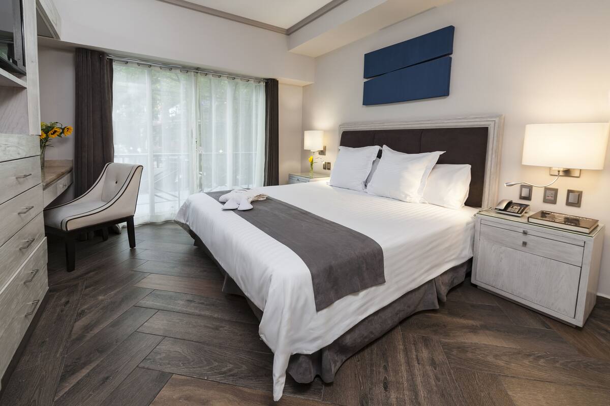 A modern hotel room with a large bed, a desk, and a chair.