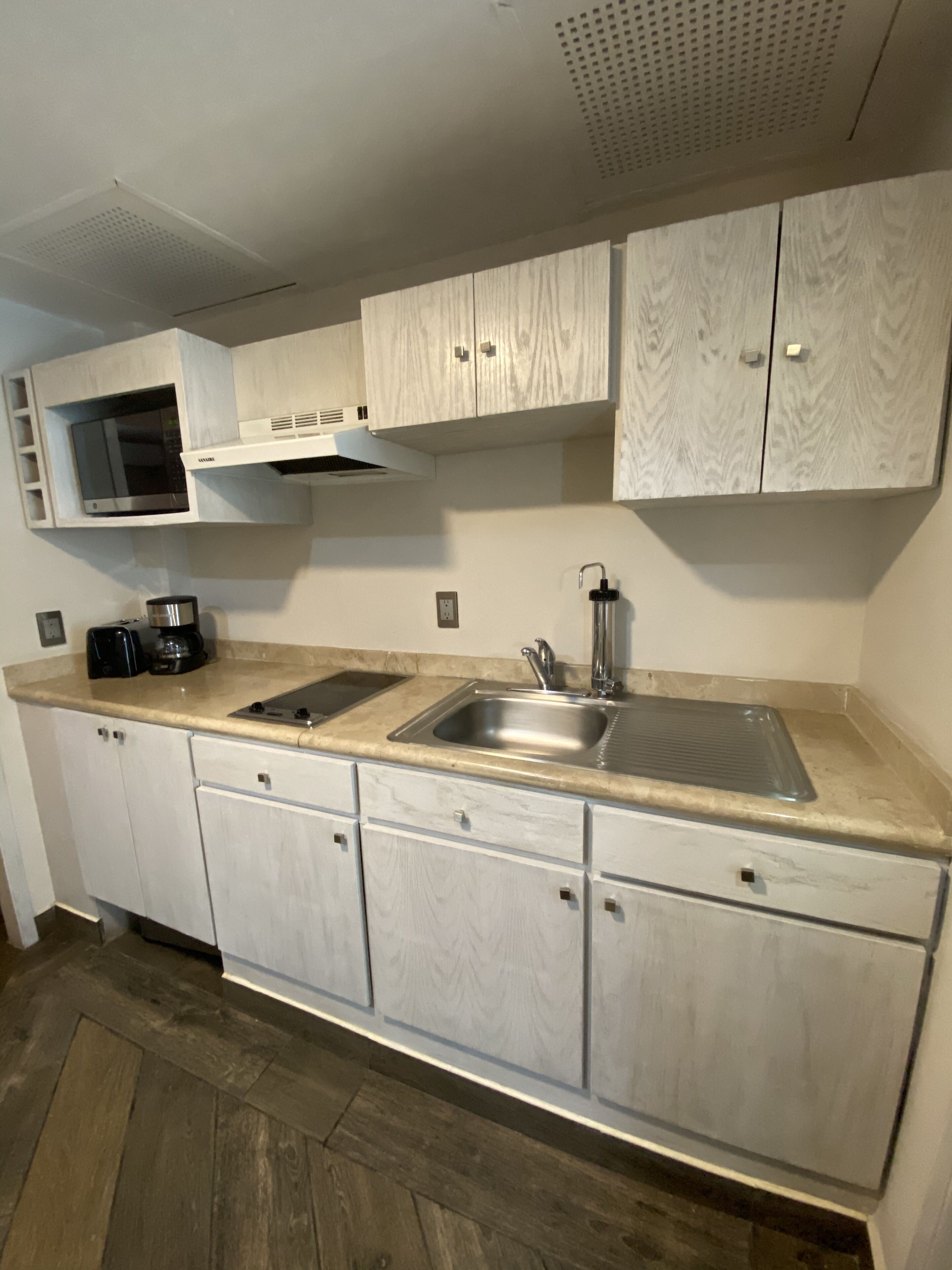 A modern kitchen with white cabinetry, a stainless steel sink, and a microwave.