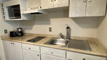 A modern kitchen with white cabinetry, a stainless steel sink, and a microwave.