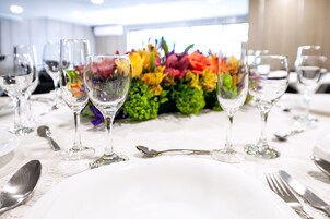 Una mesa puesta con cristalería transparente, cubertería y un centro de mesa floral.