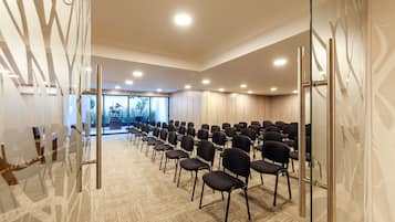 A conference room with rows of chairs, a glass partition, and a view of greenery outside.