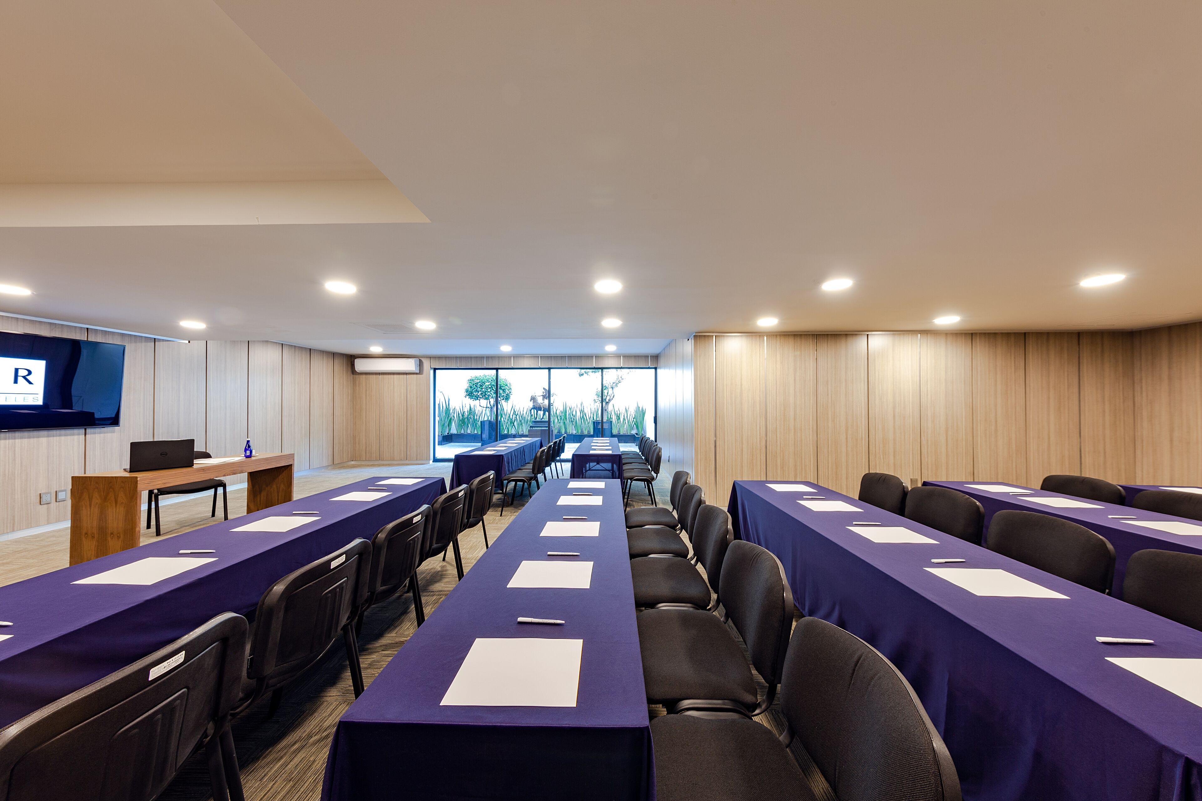 A conference room with long tables, chairs, and a laptop on a desk.