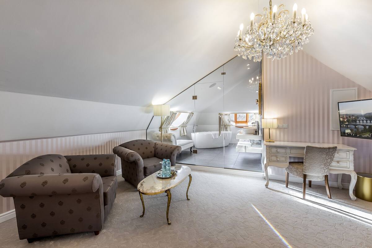 A spacious loft bedroom with a large window, a chandelier, and a view of the city.