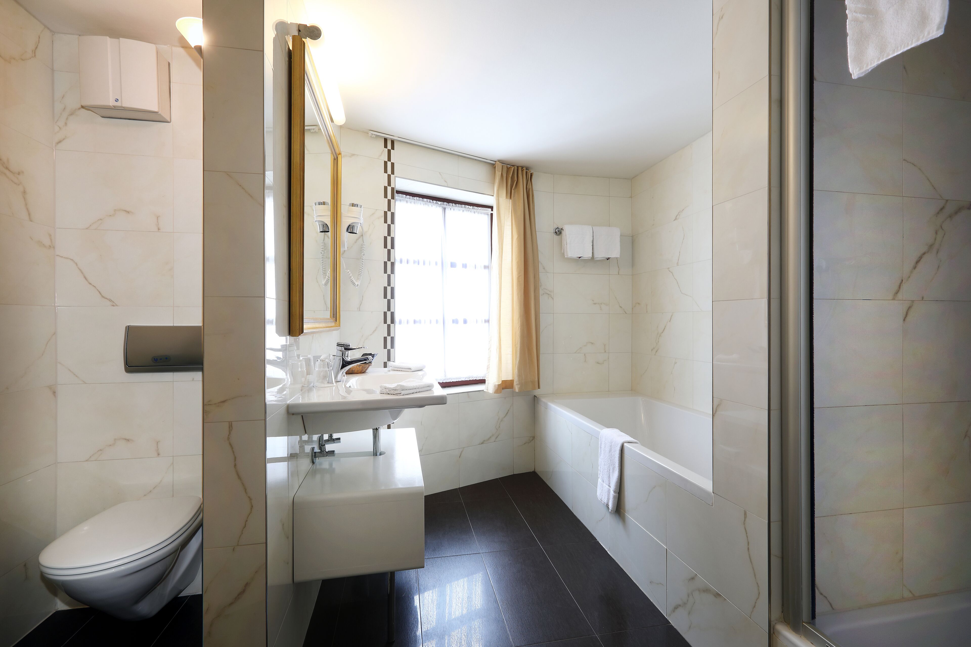 A modern bathroom with a toilet, sink, and bathtub.