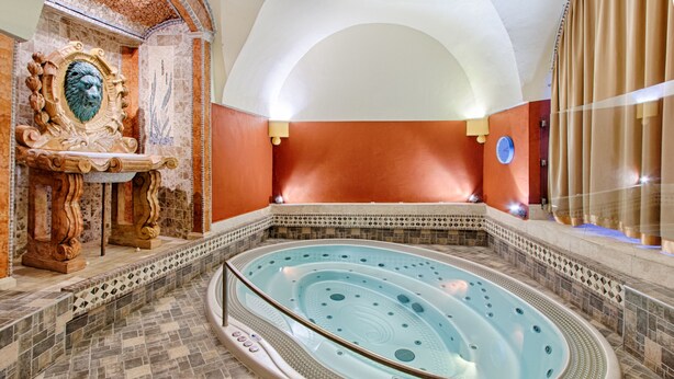 A spa area with a hot tub, ornate wall decor, and a tiled floor. - Hotel Hoffmeister (Prague)