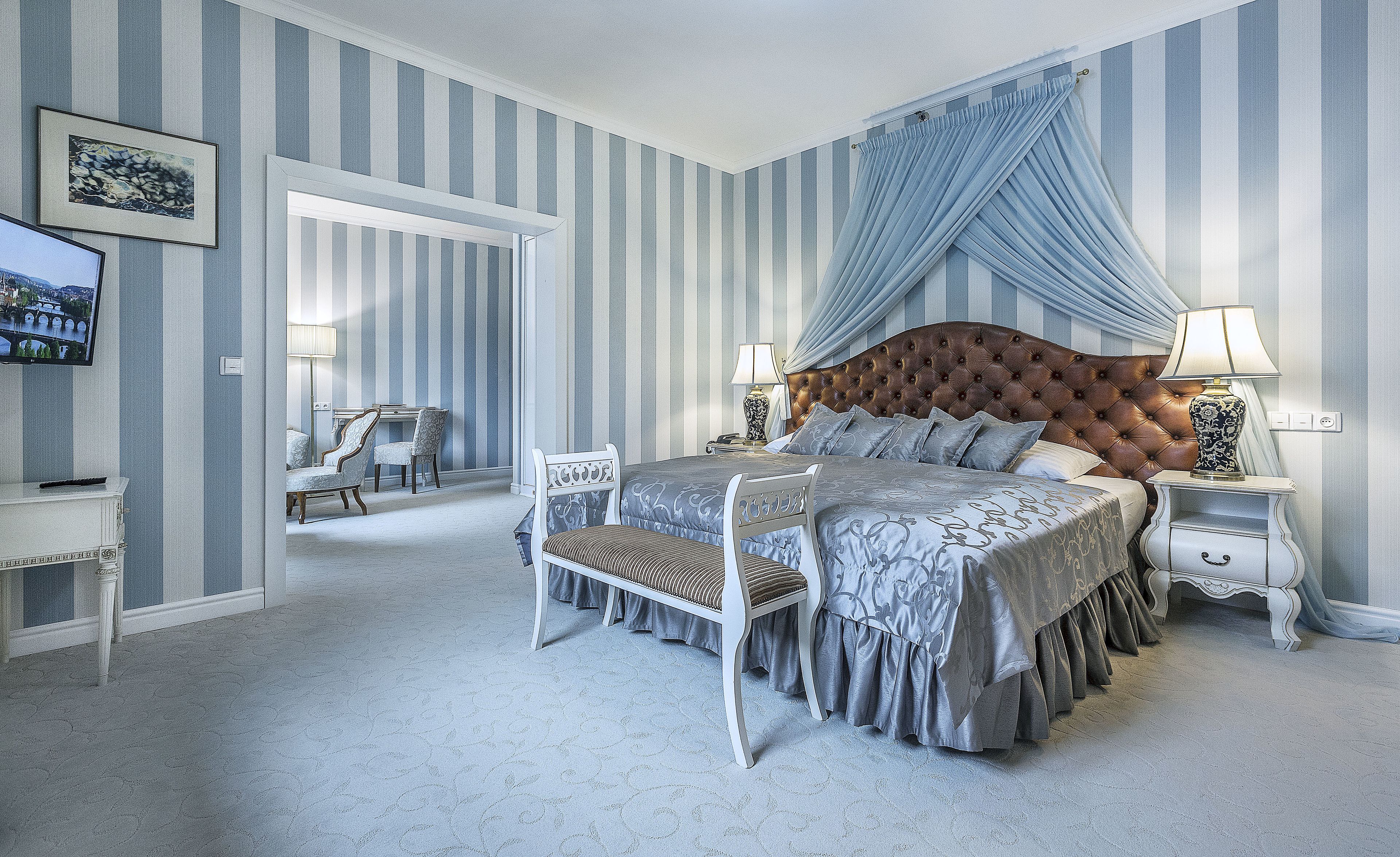 Ein Schlafzimmer mit einem großen Bett, einem Fernseher und einem Schreibtisch mit Stühlen.